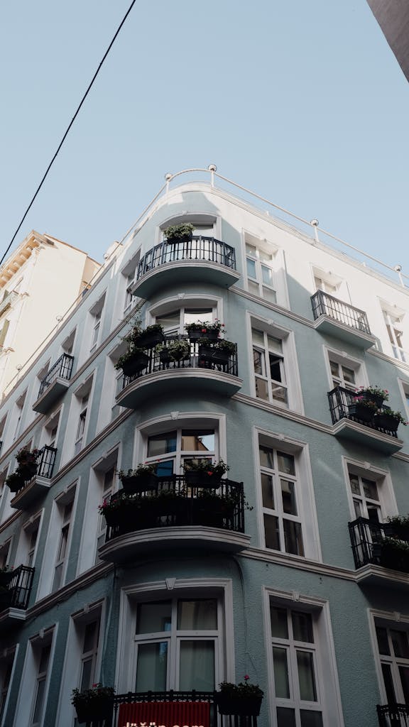 Classical apartment building exterior featuring elegant balconies and glass windows in a low angle view.